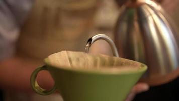 Slow-motion-bild av barista som gör en varm kaffe med filterdroppande vattenprocess, hemlagat kaffe på morgonen hemma eller café, vintage handbryggande vatten över rostade kaffebönor video