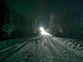 snowy road on a moonlit winter night in the village photo