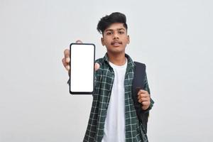 Young indian collage boy showing smartphone screen on white background. photo