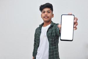 Young indian collage boy showing smartphone screen on white background. photo