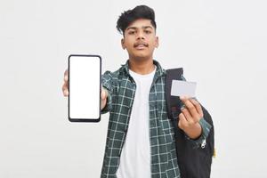 estudiante universitario indio mostrando pantalla móvil y tarjeta sobre fondo blanco. foto