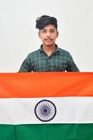 Young indian man holding indian national flag in hand over white background photo