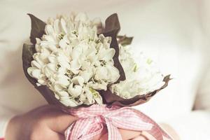 lilies of the valley bouquet in girl's hands. close up picture. Small flowers beige toned.