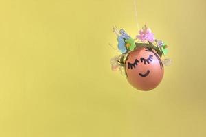huevo de pascua natural con cara pintada divertida y corona de flores dulces foto
