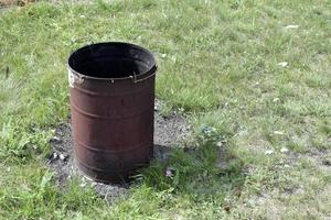 Burnt trash can on the grass in summer photo