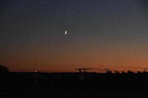 paisaje rural nocturno iluminado por la luna con cielo azul foto