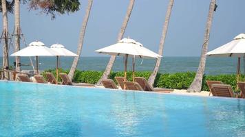 guarda-chuva com piscina ao redor da piscina com fundo do mar oceano - conceito de férias e férias video