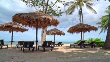 Sonnenschirm und Liegestuhl mit Kokospalme und Meeresstrandhintergrund und Dämmerungshimmel - Urlaub und Urlaub