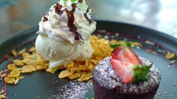 pastel de chocolate lava con helado de fresa y vainilla en plato negro