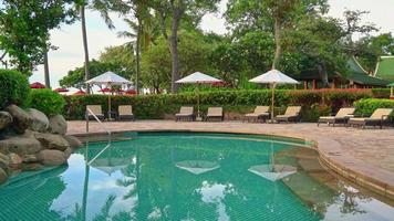 beau parapluie de luxe et chaise autour de la piscine extérieure avec cocotier au coucher du soleil ou au lever du soleil - concept de vacances et de vacances video