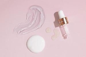 Smears of various cosmetic products and a pipette on a nude background. Top view cosmetics photo