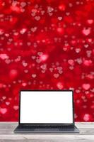 Mock-up laptop on a wooden table on red heart-shaped bokeh background vertical format photo