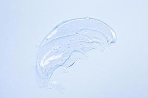 Thick transparent gel, cosmetics. soap texture, antiseptic, hyaluron smear on a blue top view photo