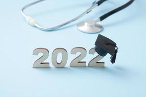 Number 2022 wearing a graduate cap with medical stethoscope on a blue background. Medical education in the 2022 concept photo