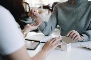 estate agent giving house keys to woman and sign agreement in office photo