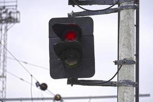 Railway traffic light with red light on sky background photo