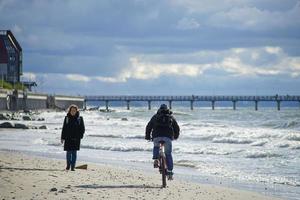 Zelenogradsk, Russia-may 17, 2016 - An elderly woman walks along the sandy beach towards the cyclist. photo