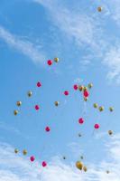 Many red and gold balloons fly under the blue sky and white clouds photo