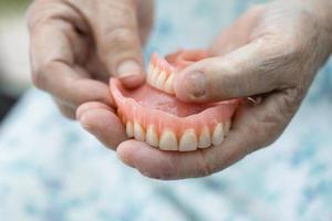 Asian senior or elderly old woman patient holding to use denture in nursing hospital ward, healthy strong medical concept photo