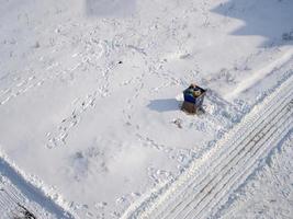 Garbage container near the road on snowy ground in winter, top view photo