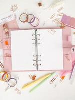 Diary opens with white and holographic page. Pink planner with cute stationery photographing in flatlay style. Top view of pink planner with business stationery photo