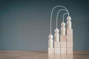 Wooden peg dolls on Stack of wooden blocks. Employees positions. Human resource management planning. photo