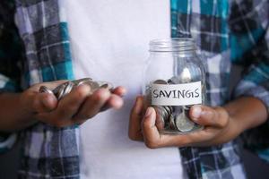 young man saving coins in a jar white sited photo