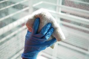 close up of person hand in gloves cleaning window glass photo