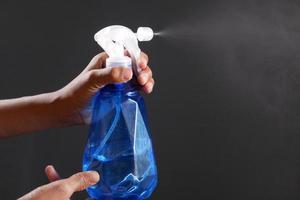 hand in blue rubber gloves holding spray bottle with copy space photo