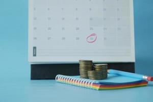 stack of coins and calendar on table photo