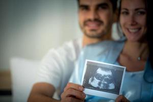 The happiness of a pregnant woman and her husband in the bedroom with the ultrasound film