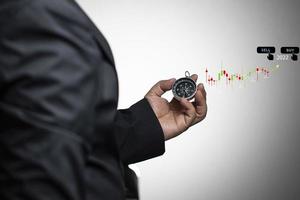 Businessman holding compass in hand deciding 2022 stock trading trends, buying or selling decision through candlestick chart. photo