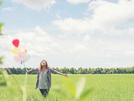 Happy young beautiful hipster woman holding colorful balloons in grassland enjoy life and happy. photo