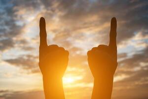 Silhouette of hand shape with sky sunset background. photo