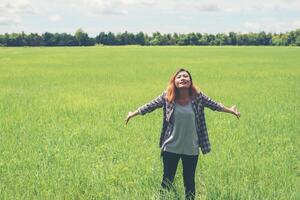 libertad joven hermosa mujer estirando sus brazos hacia el cielo disfruta y feliz con aire fresco en los pastizales. foto