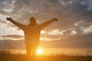 Silhouette of woman standing on field during sunset. photo