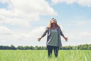 libertad joven hermosa mujer estirando sus brazos hacia el cielo disfruta y feliz con aire fresco en los pastizales. foto