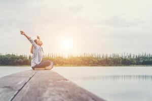 joven hermosa mujer hipster sentada en el lago relajándose con aire fresco. foto