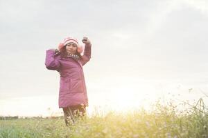 Young girl spreading hands and joy with nature while winter time at sunset background. photo