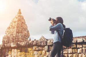 joven y atractiva mujer fotógrafa turista con mochila que viene a tomar fotos en el antiguo templo de peldaño fantasma en tailandia.