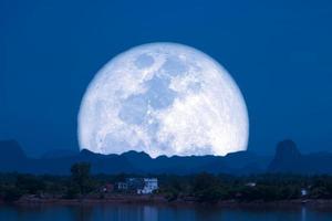 luna llena de nieve en el cielo nocturno silueta trasera montaña colina sobre el lago foto