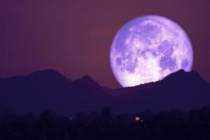 luna rosa en el cielo nocturno de vuelta sobre la montaña silueta foto