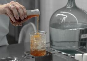 Barista hand holding Lab Borosilicate Glass Beaker Mixing tea drink beverage In Chemistry Bar Beaker Cocktail.