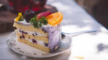 cerrar rebanada pastel de frutas de cumpleaños en placa violeta deliciosa crema en capa