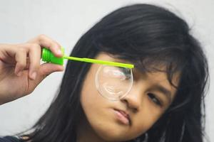 A girl holding a bubble maker and blowing them out. photo