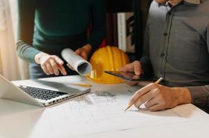 Two colleagues discussing data working and tablet, laptop with on on architectural project at construction site photo