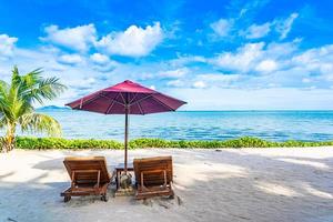 Beautiful landscape of beach sea ocean with empty chair deck and umbrella nearly coconut palm tree with white cloud and blue sky photo
