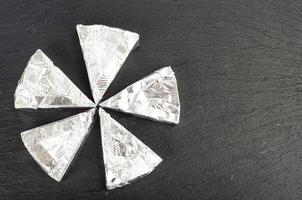 Cheese triangles in foil on black. Studio Photo