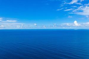 Wide aerial panorama of deep blue ocean. Relaxing minimalistic seascape with small fluffy clouds. Idyllic nature scenic drone view. Endless sea horizon, tranquil view photo