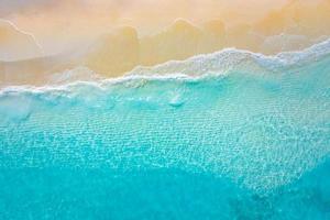 paisaje marino de verano hermosas olas, agua de mar azul en un día soleado. vista superior desde drone. vista aérea del mar, increíble fondo de naturaleza tropical. Hermoso mar brillante con olas salpicando y concepto de arena de playa foto